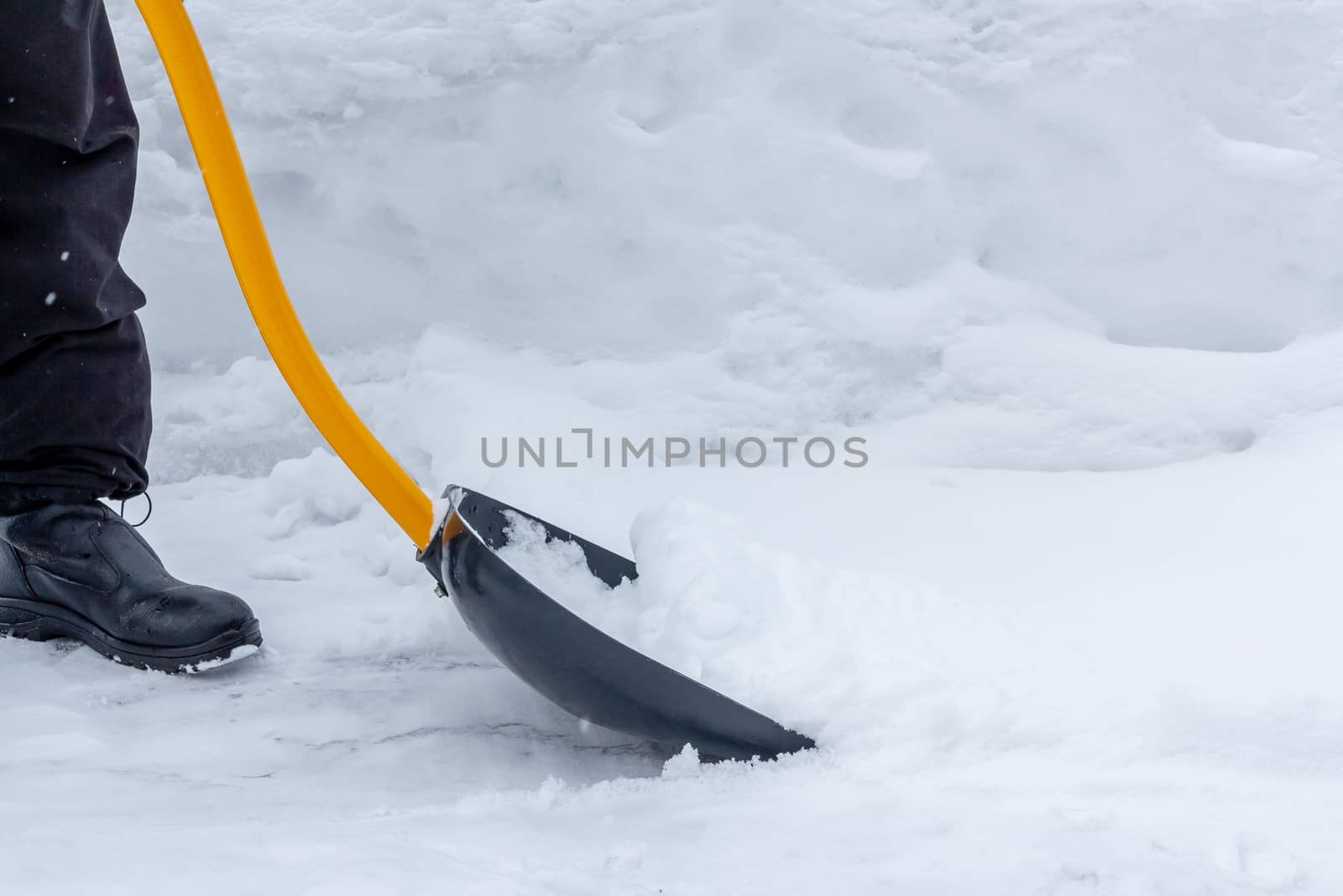 A man cleans snow in the yard with a shovel after a heavy snowfall.