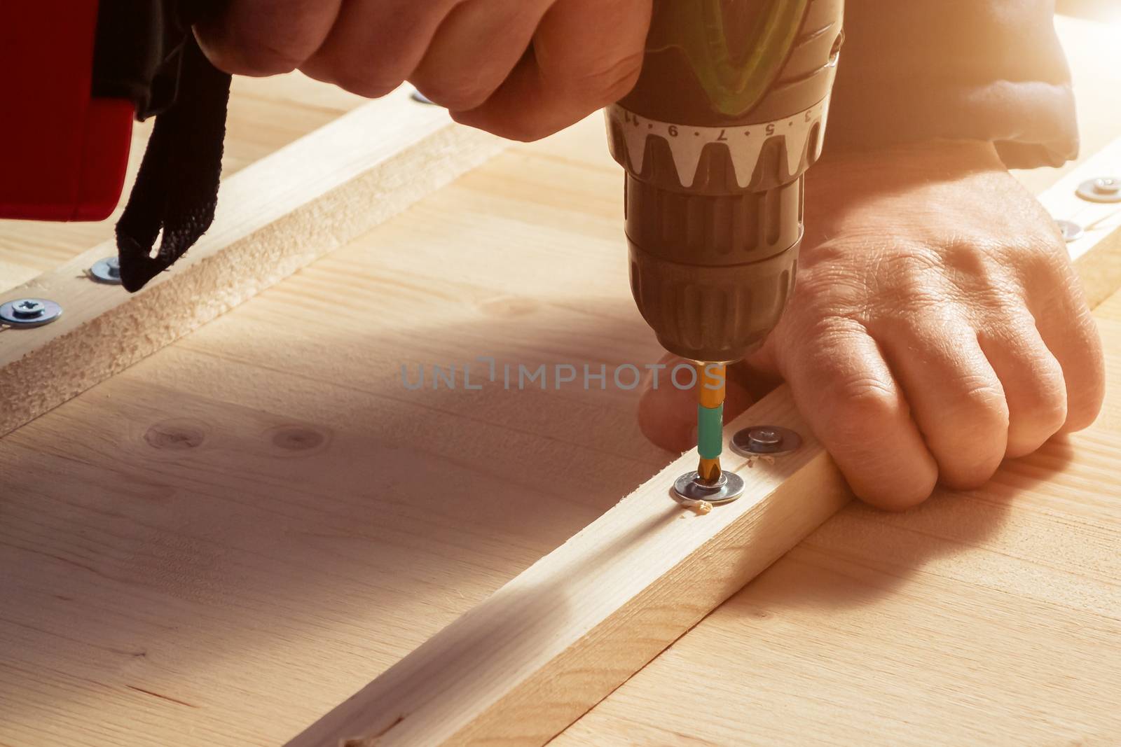 Male hands screw wooden blocks to the boards with a screwdriver by galsand
