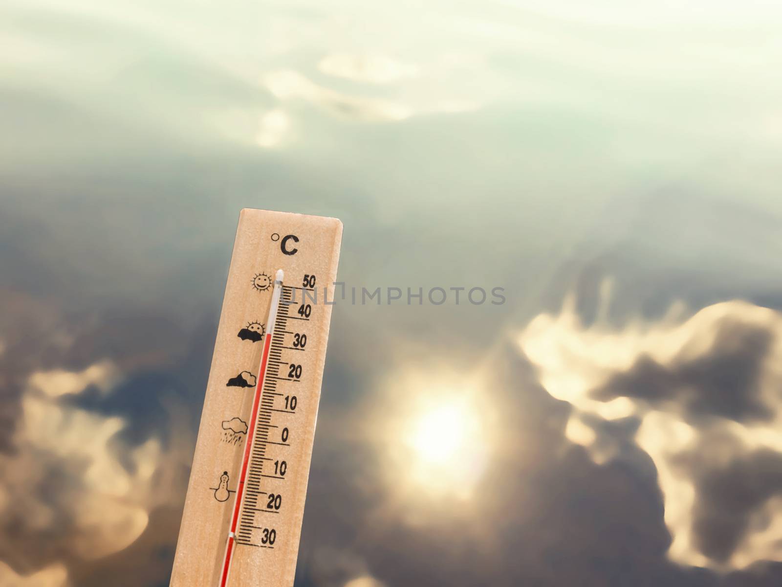 Thermometer showing 30 degrees of heat against the backdrop of lake water with the reflection of clouds and the sun by galsand