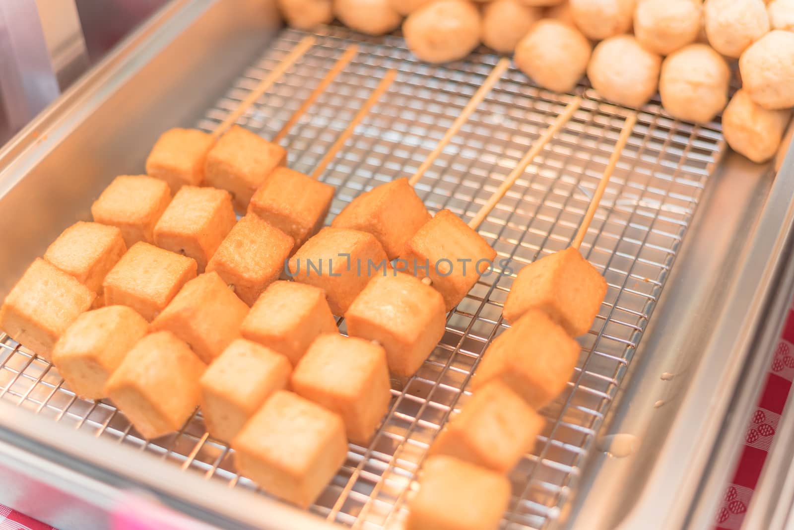 Close-up, selective focus of skewers with fried tofu cubes at farmer market stand in America. Tofu breaded, vegetarian food