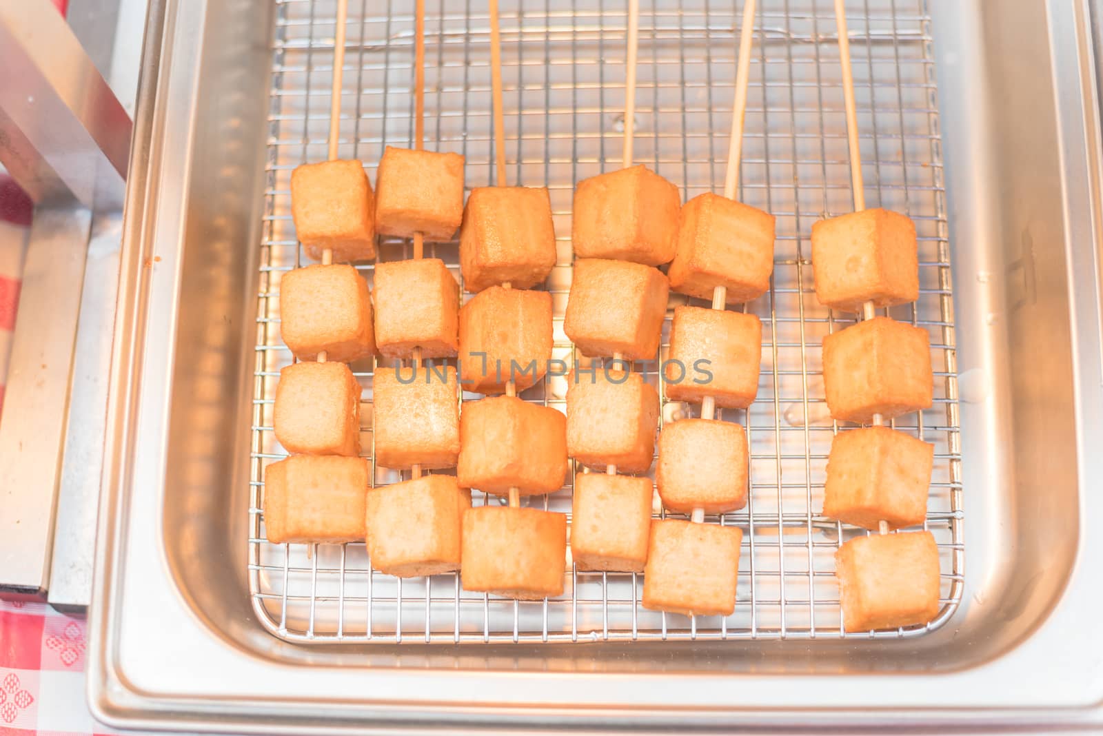 Skewers of fried tofu cubes on frying pan by trongnguyen