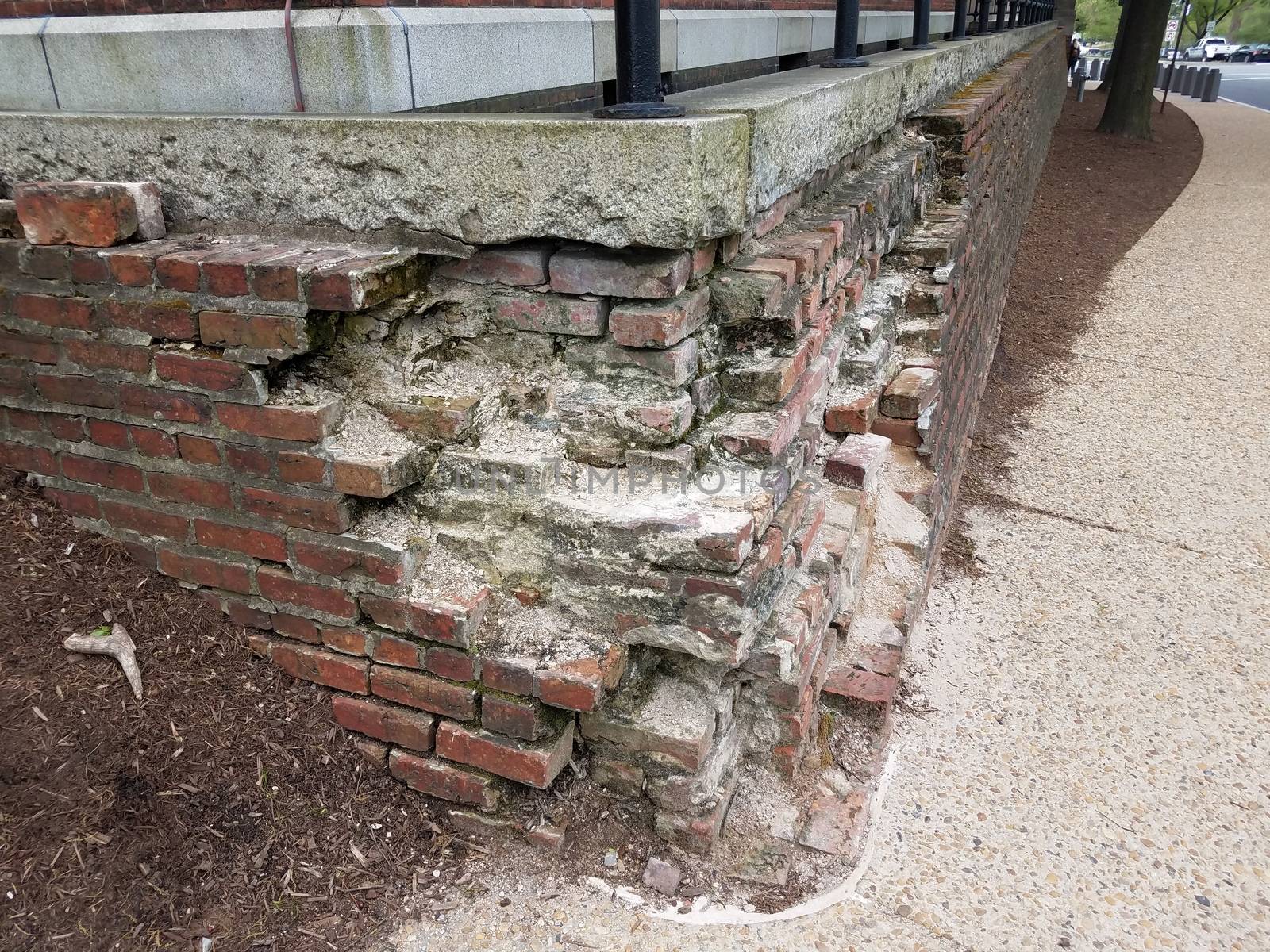 broken or damaged brick wall or masonry with cement sidewalk