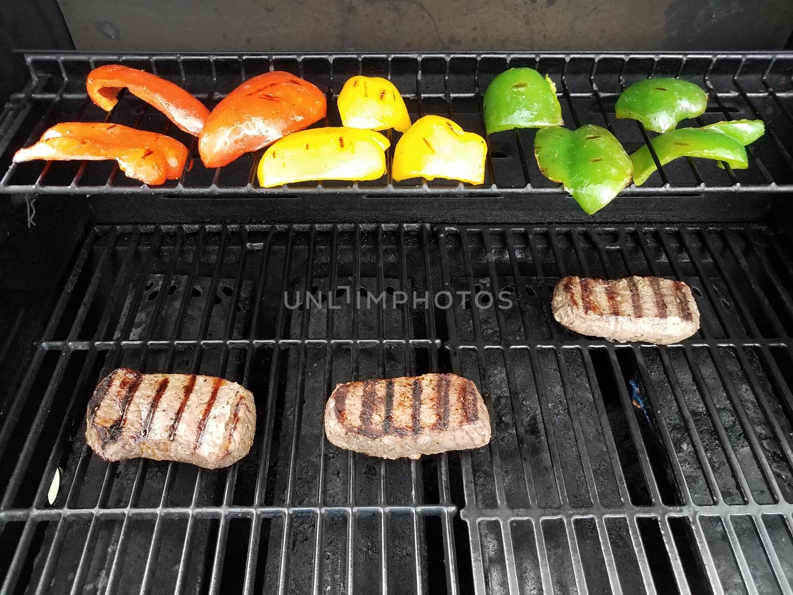 steak and bell peppers cooking on a barbecue grill