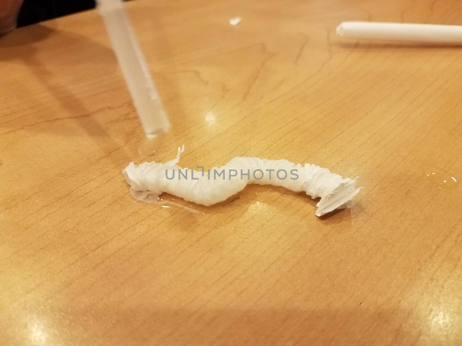 plastic straw and wet paper straw cover or wrapper on brown wood table