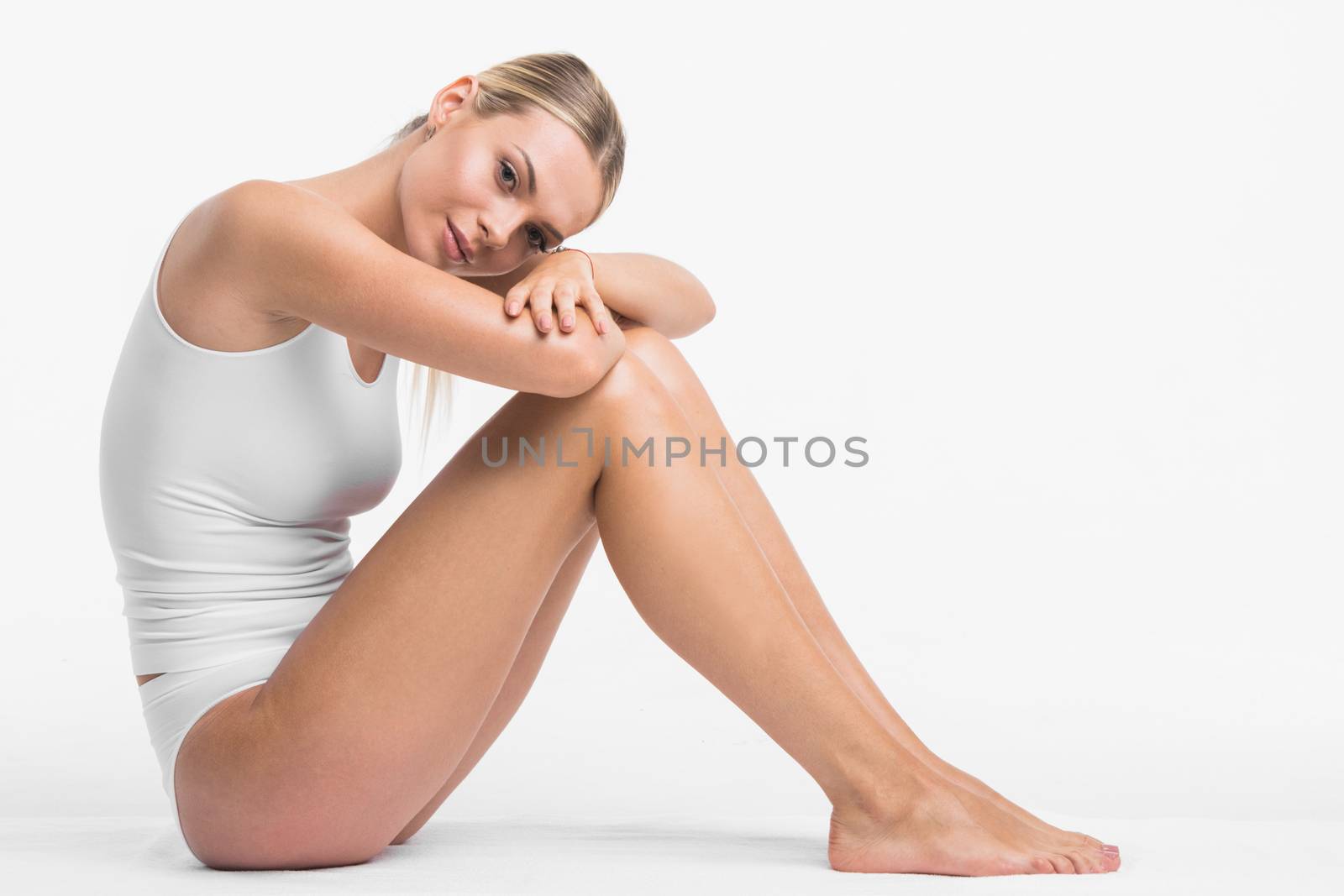 Young beautiful woman in white cotton underwear sitting on white background