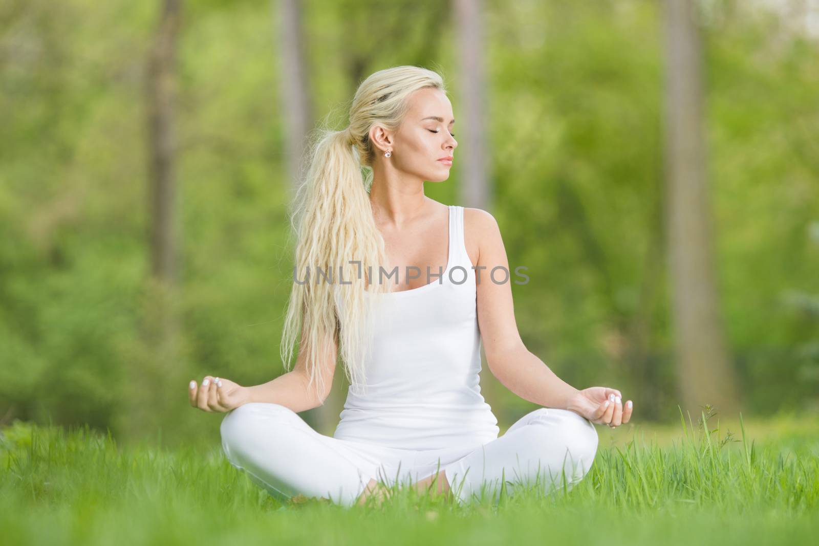 Young woman doing lotus yoga in spring park