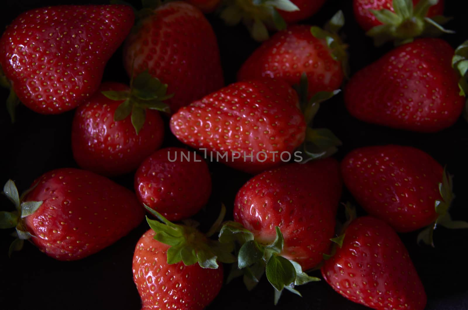 Strawberries on black background, long exposure natural light