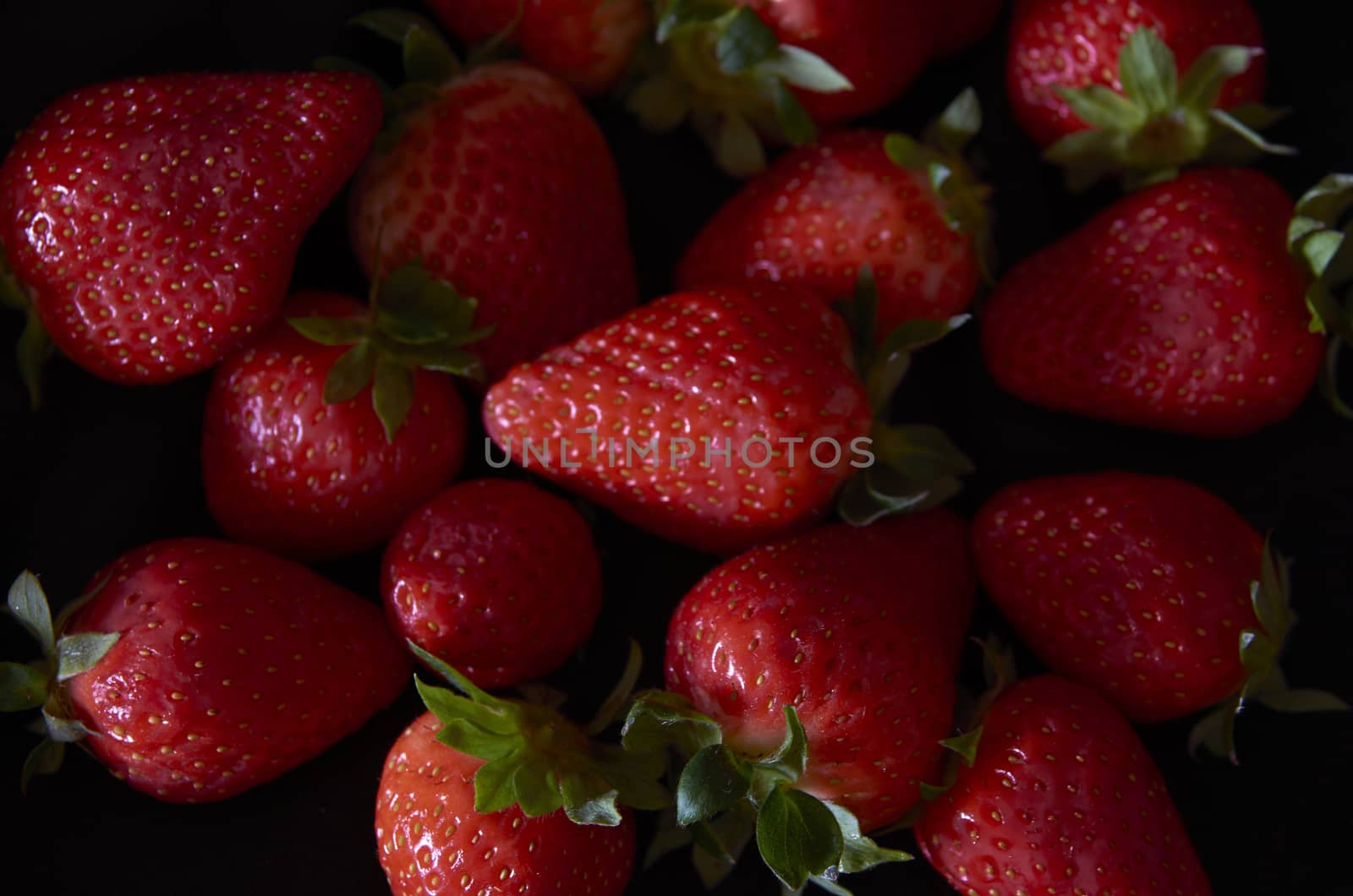 Strawberries on black background, long exposure natural light