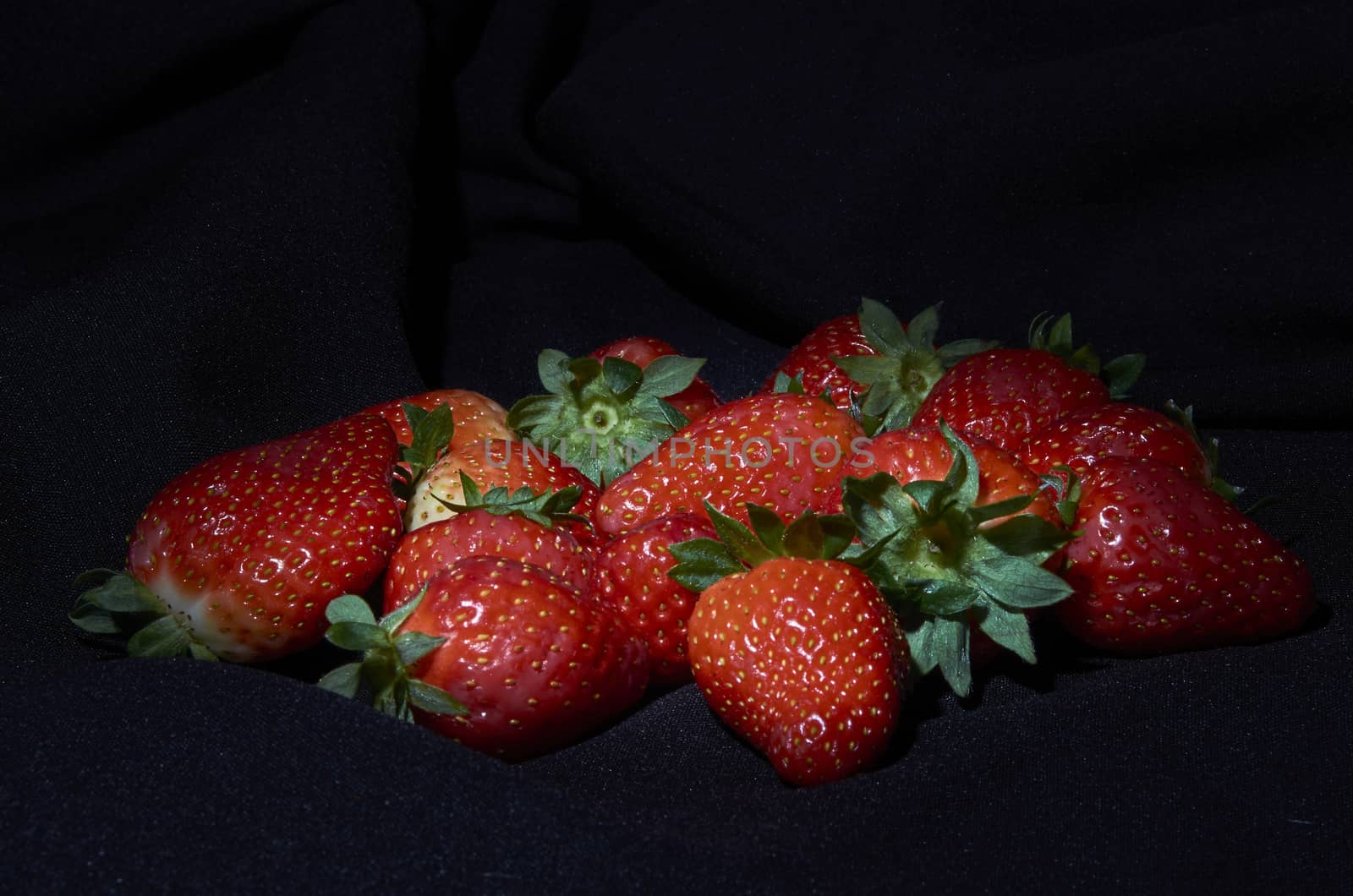 Strawberries on black background, long exposure natural light