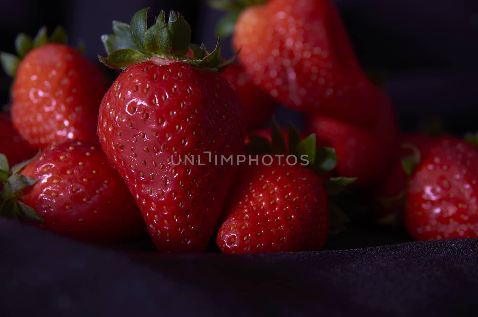 Strawberries on black background, long exposure natural light