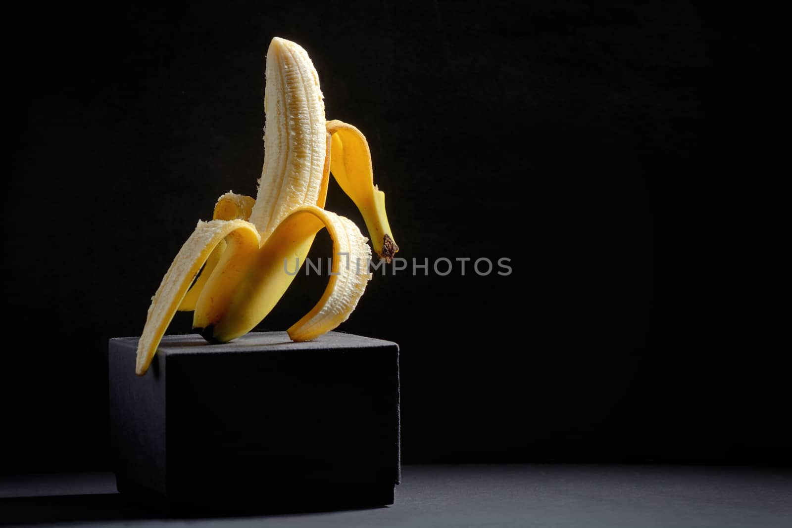 Concept with Half peeled banana on black background