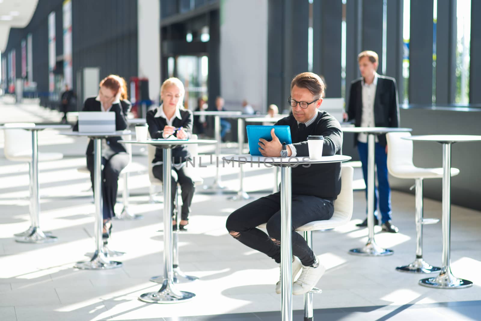Lot of business people sitting in cafe of modern office building