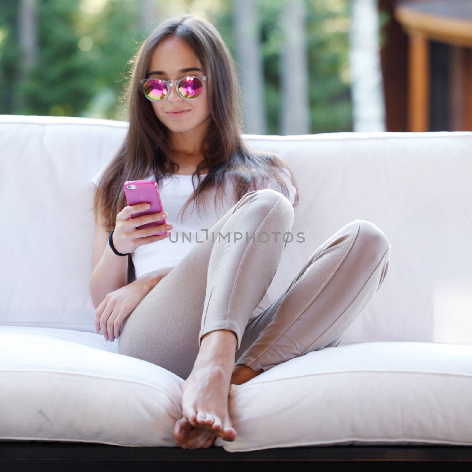 Beautiful young girl with smartphone sitting outdoors