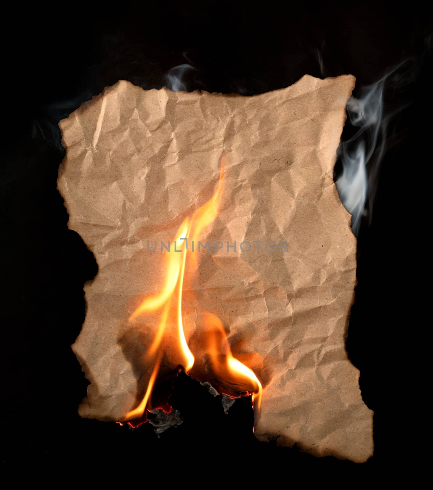 burning piece of crumpled paper on black background