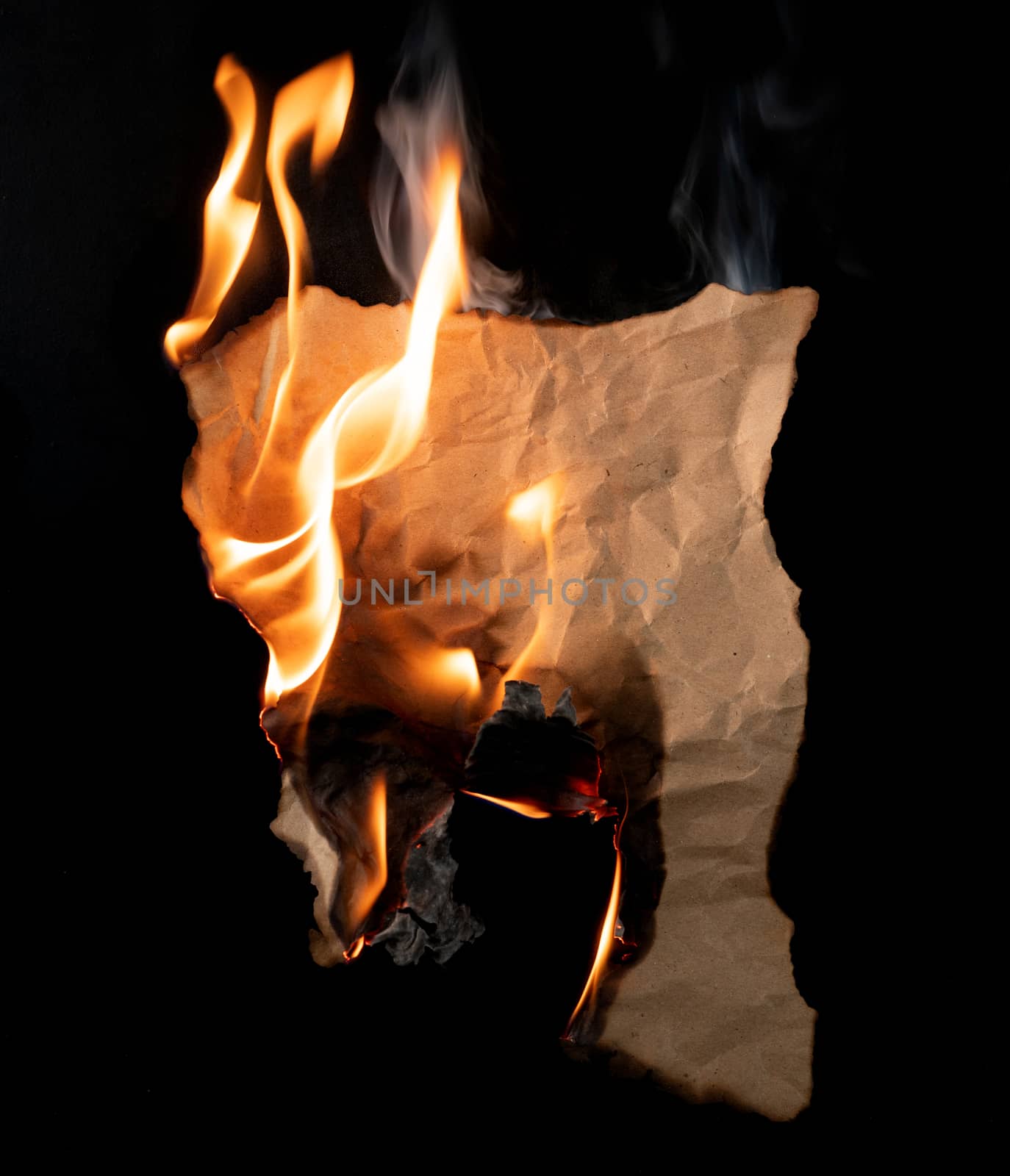 burning piece of crumpled paper on black background