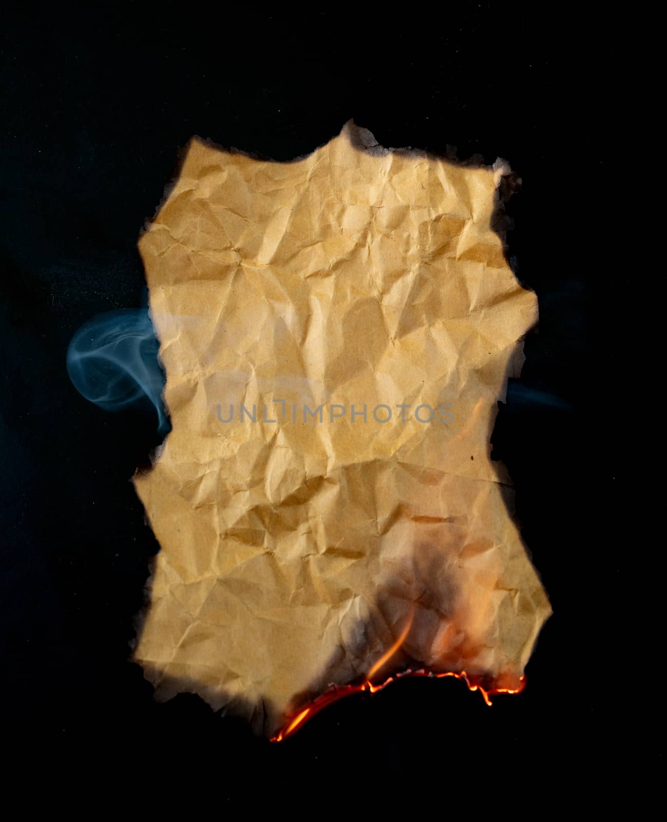 burning piece of crumpled paper on black background