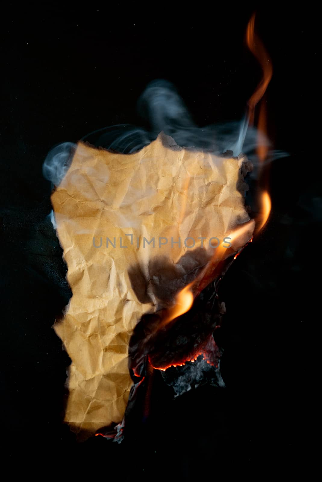 burning piece of crumpled paper on black background