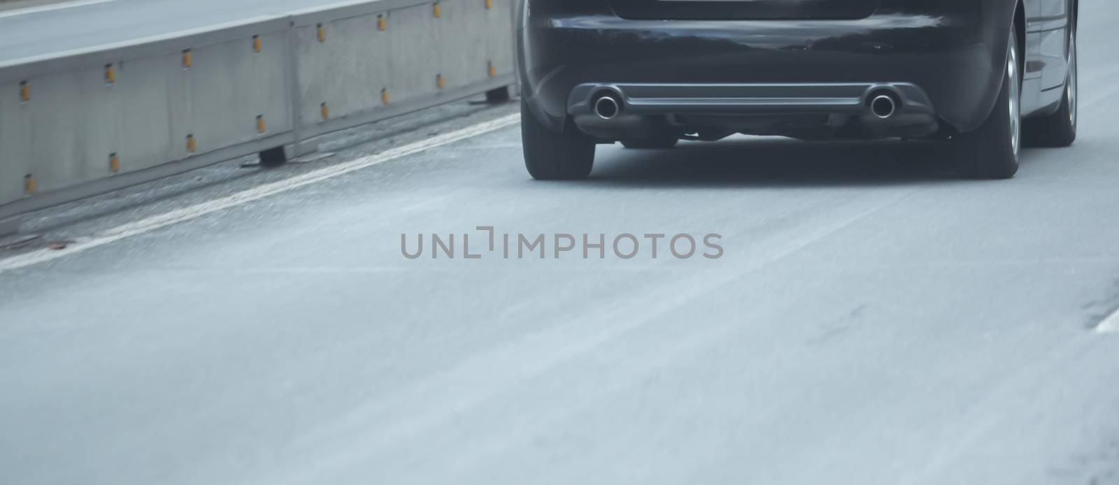 Rear and exhaust of a car on the highway by sandra_fotodesign