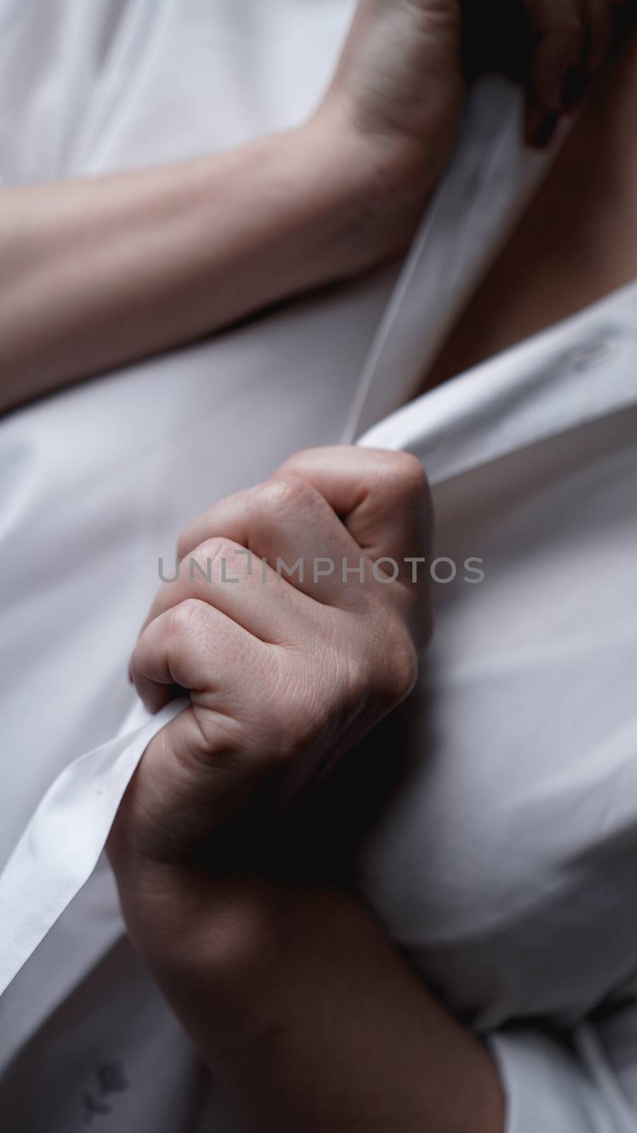 A woman holds her hands for a mens white shirt. Photo without face
