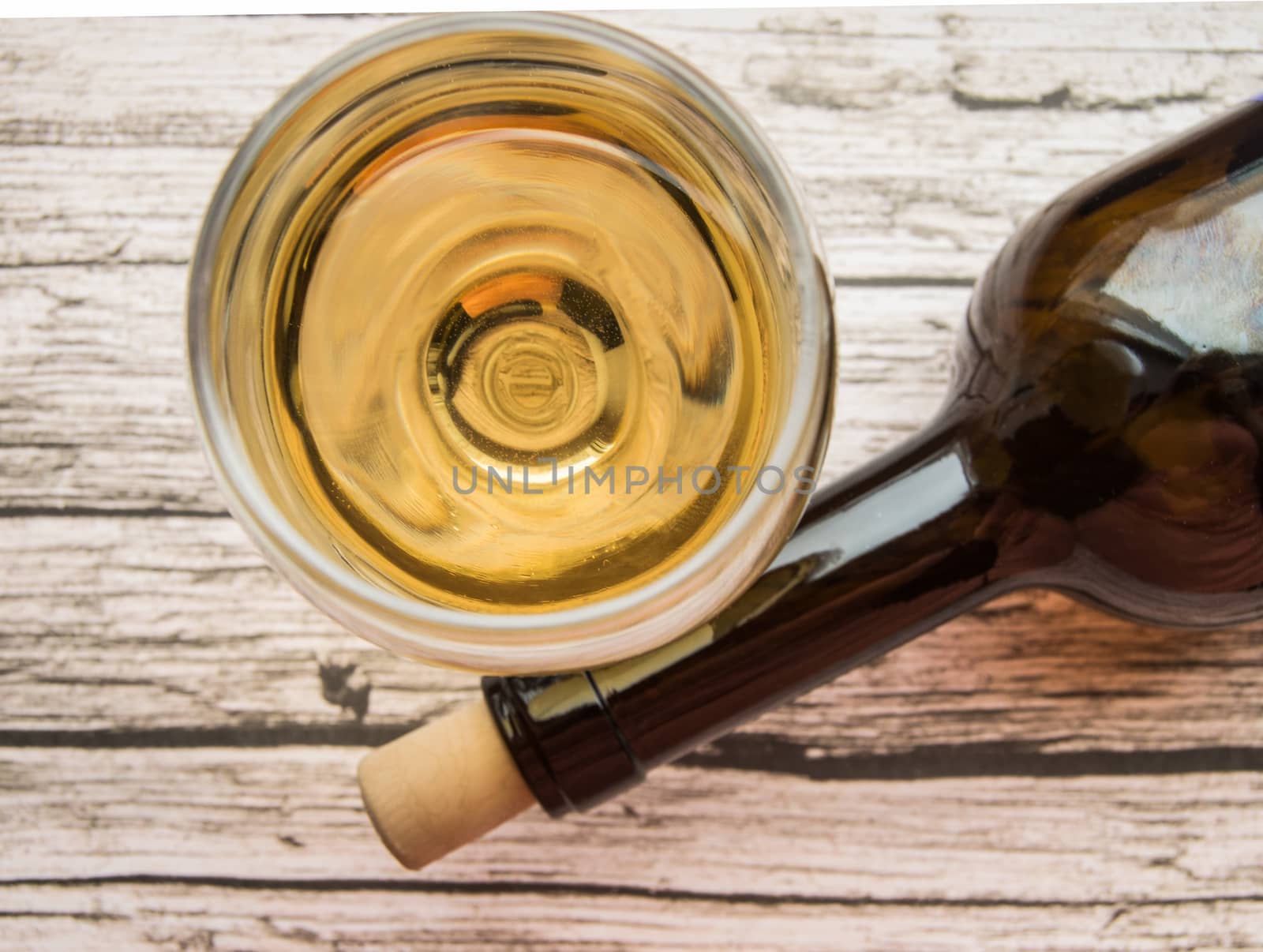 Top view of a glass of dry white wine and a bottle lying on an old wooden background by claire_lucia
