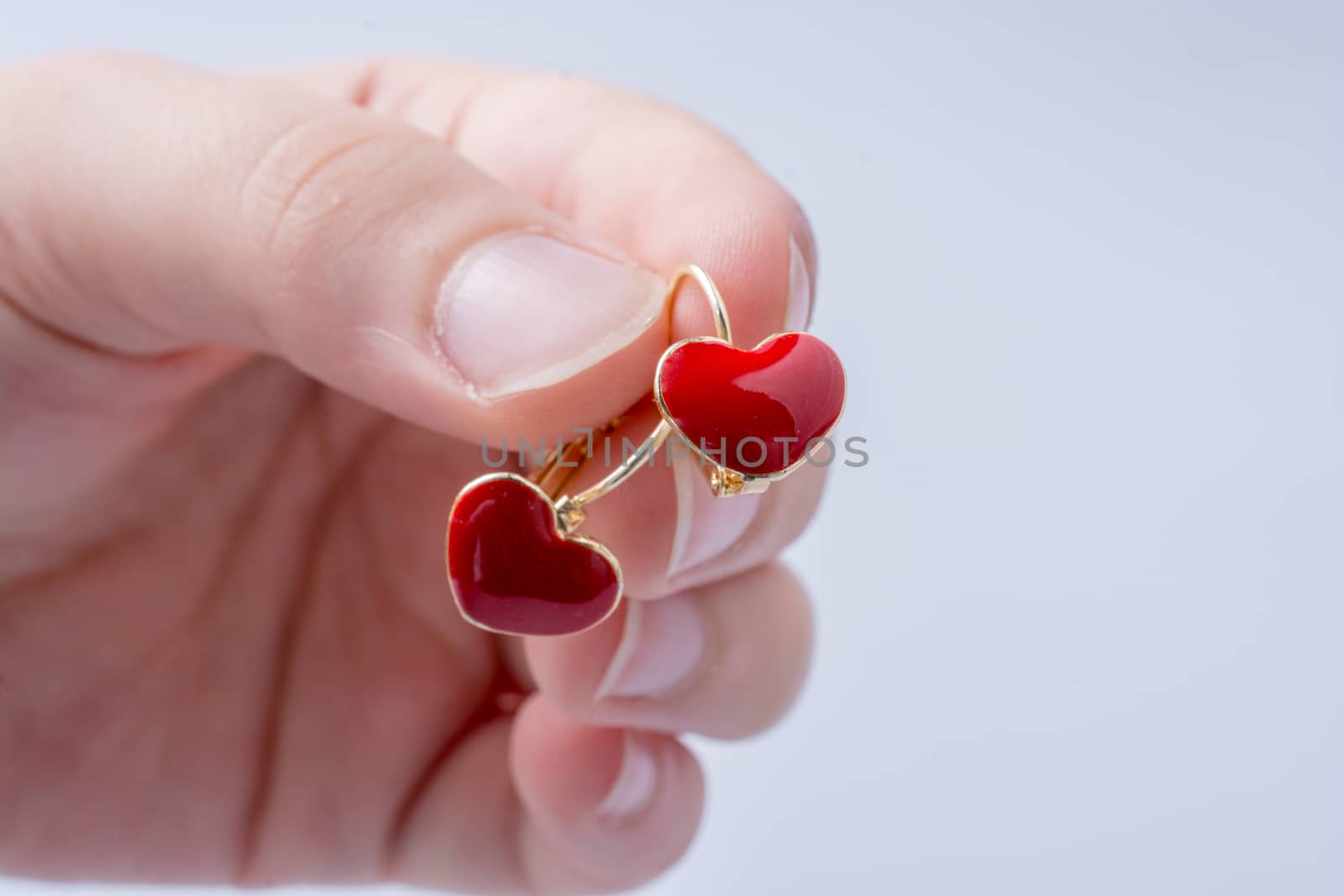 Heart shaped earring in hand on white by berkay