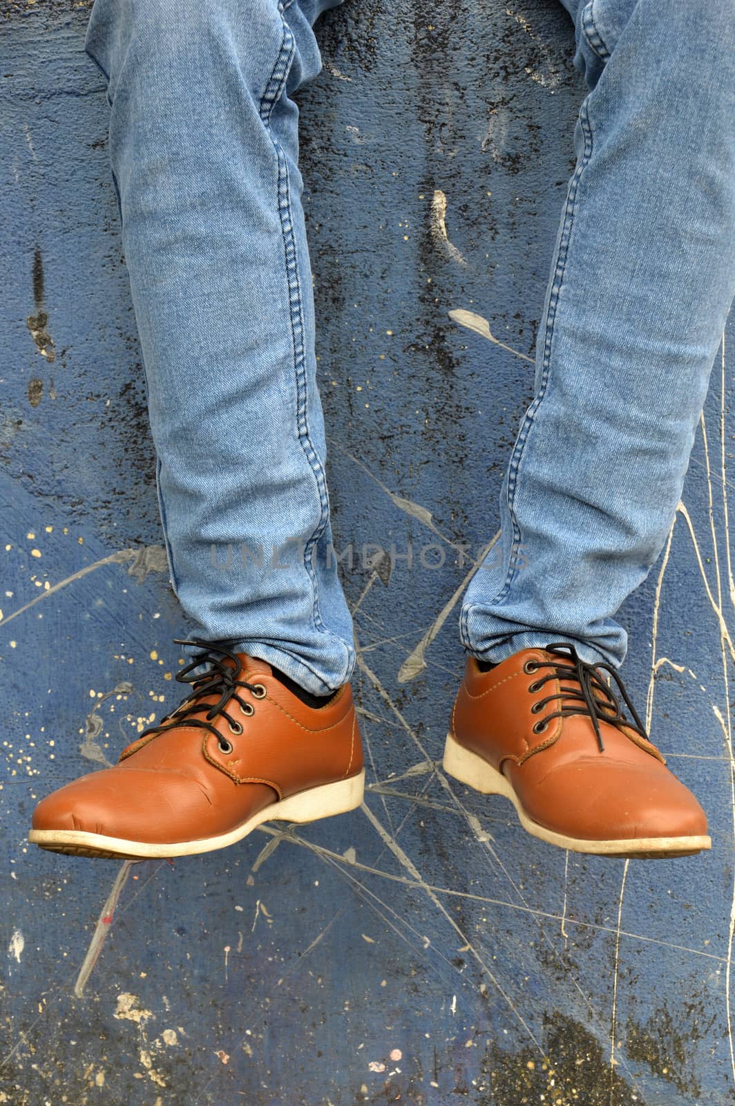 leather shoes with jeans on concrete wall