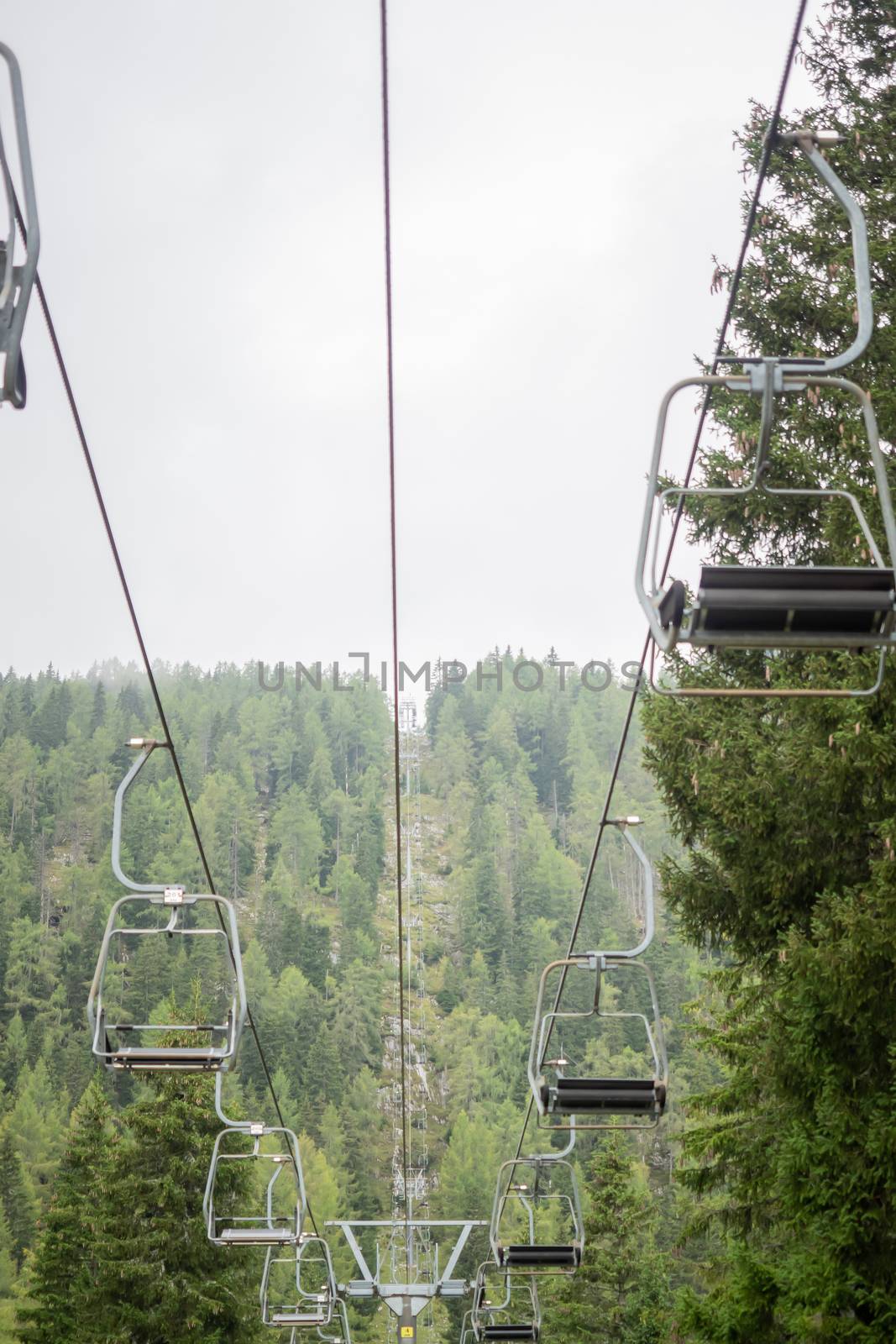 A chairlift with mountains and fog in the background by sandra_fotodesign