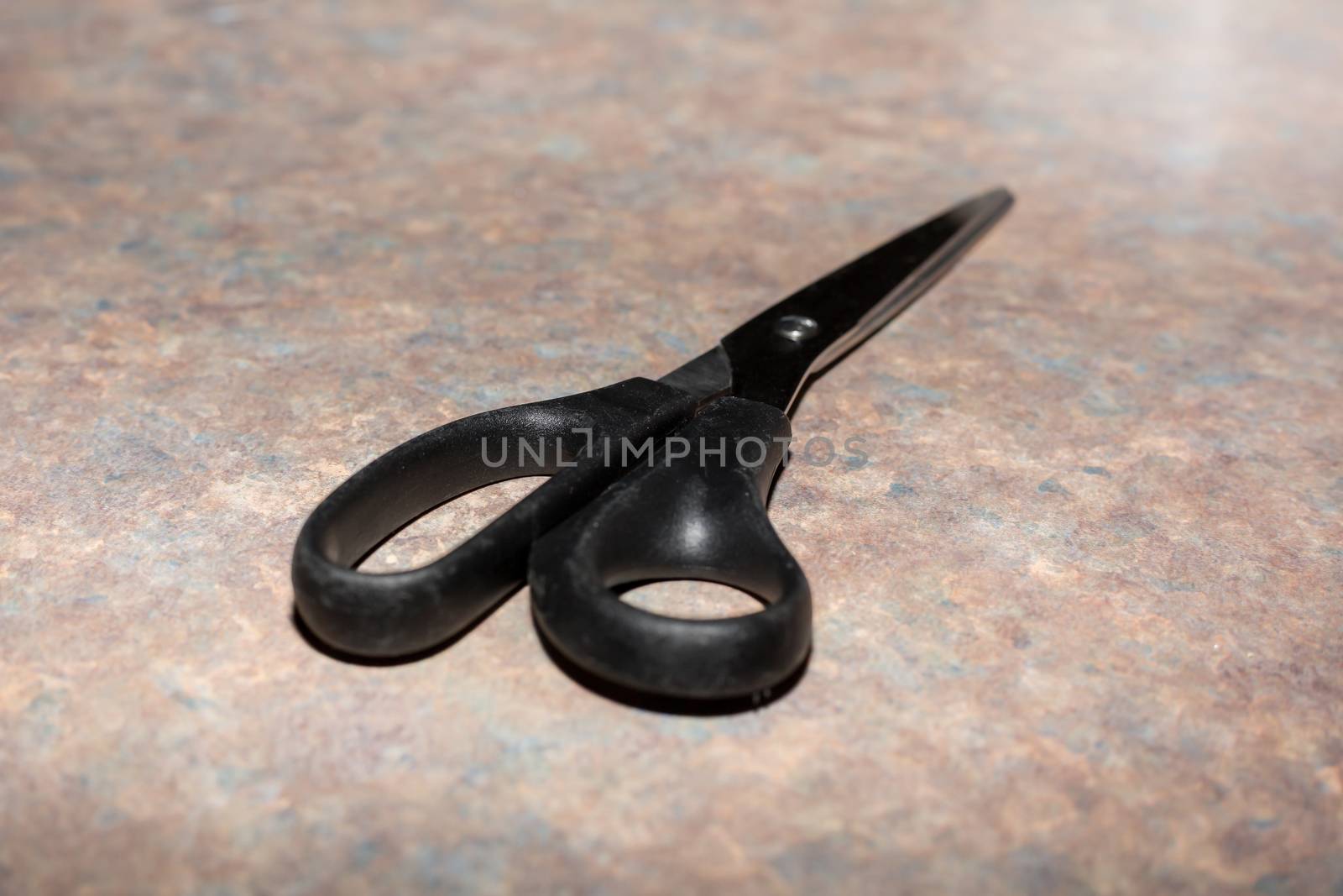 A black pair of scissors lies on the worktop
