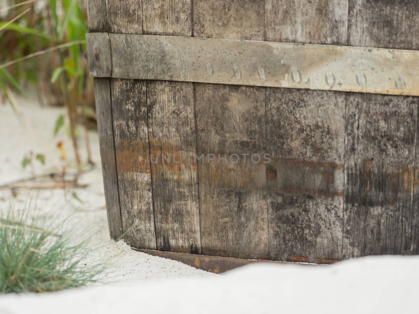 An old wooden barrel lies in the sand