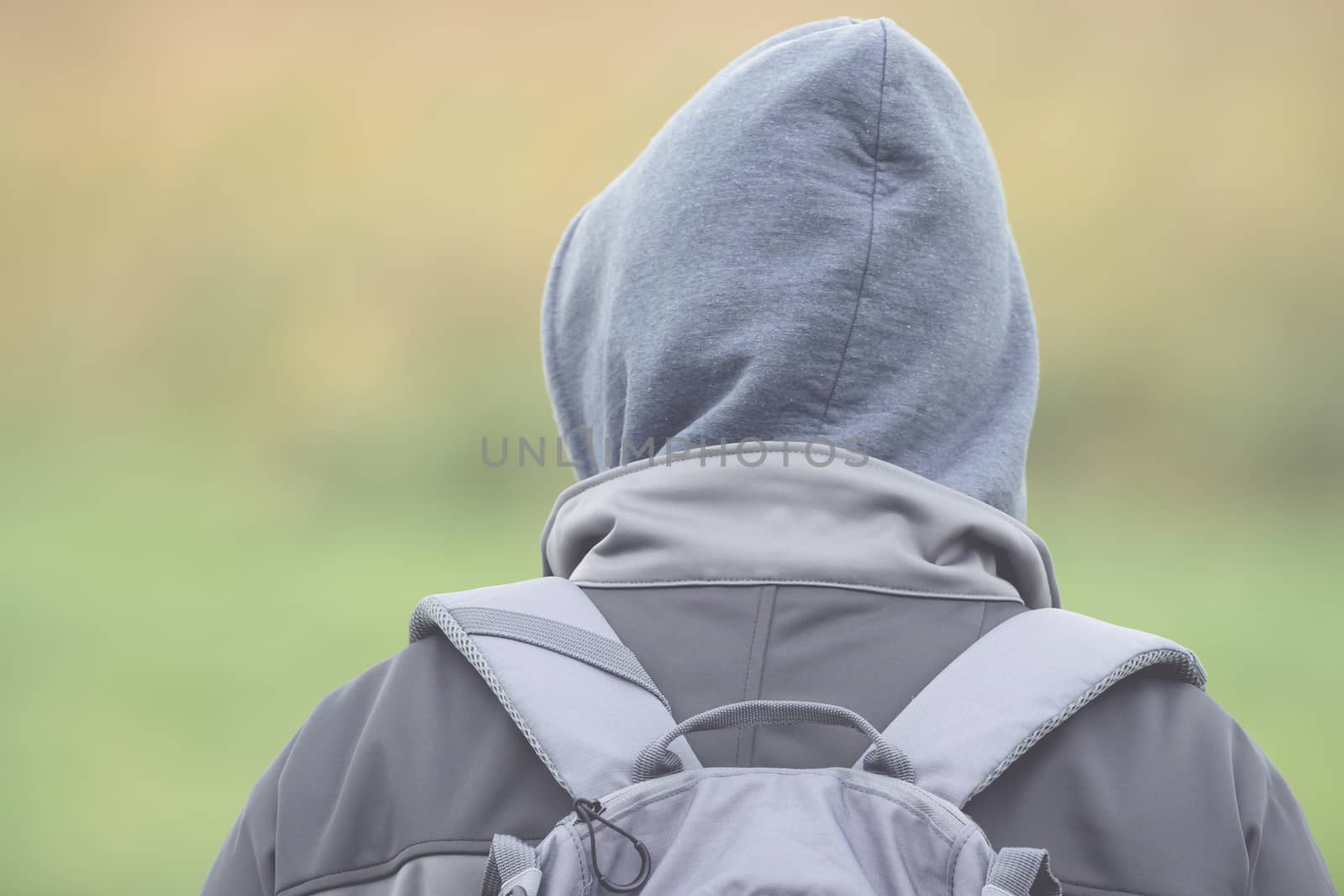 Man with hood and backpack from behind with soft bokeh