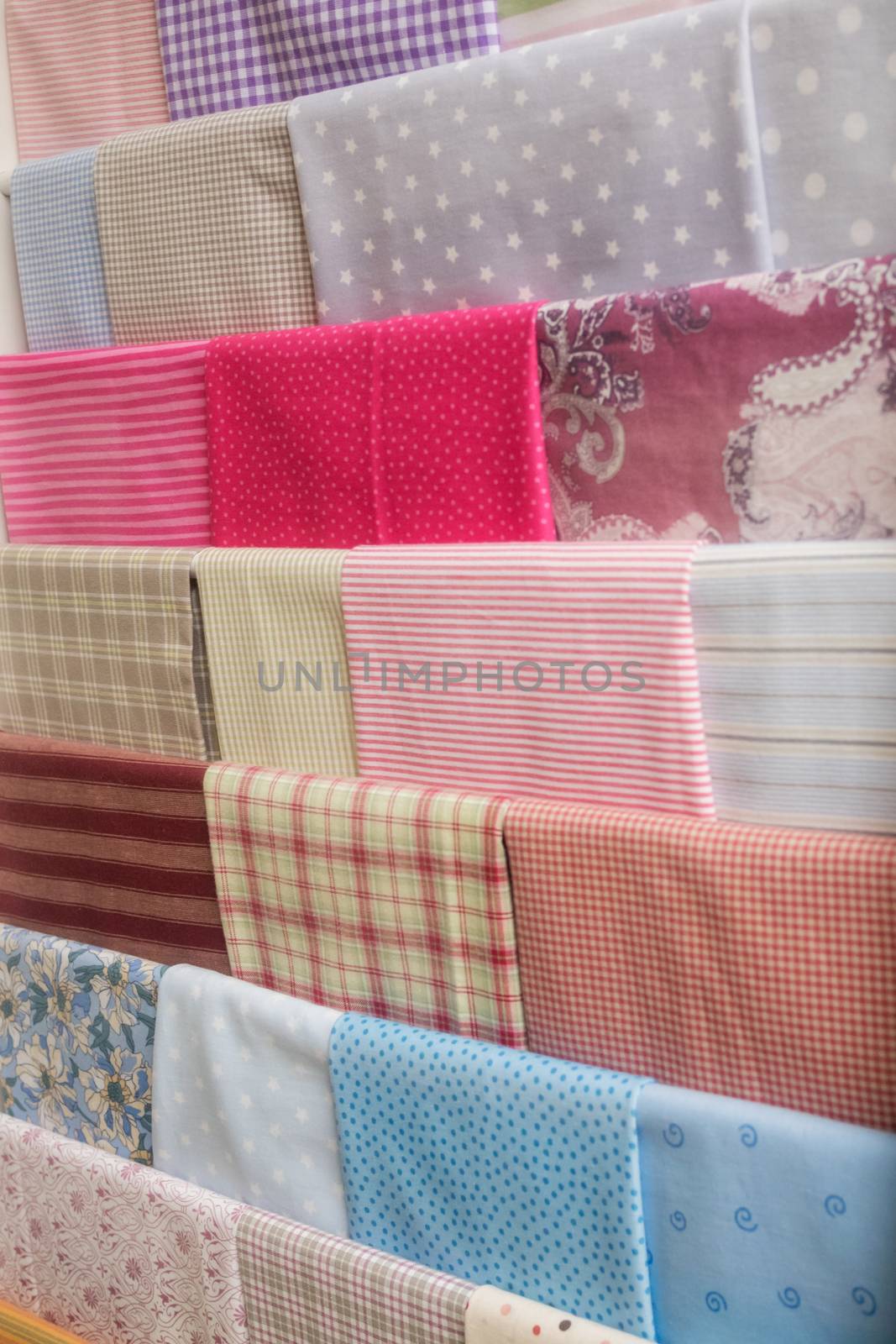 Many colorful fabrics hang on the wall by sandra_fotodesign