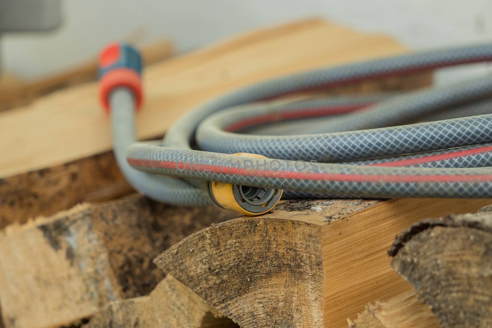 A garden hose lies on a pile of wood by sandra_fotodesign