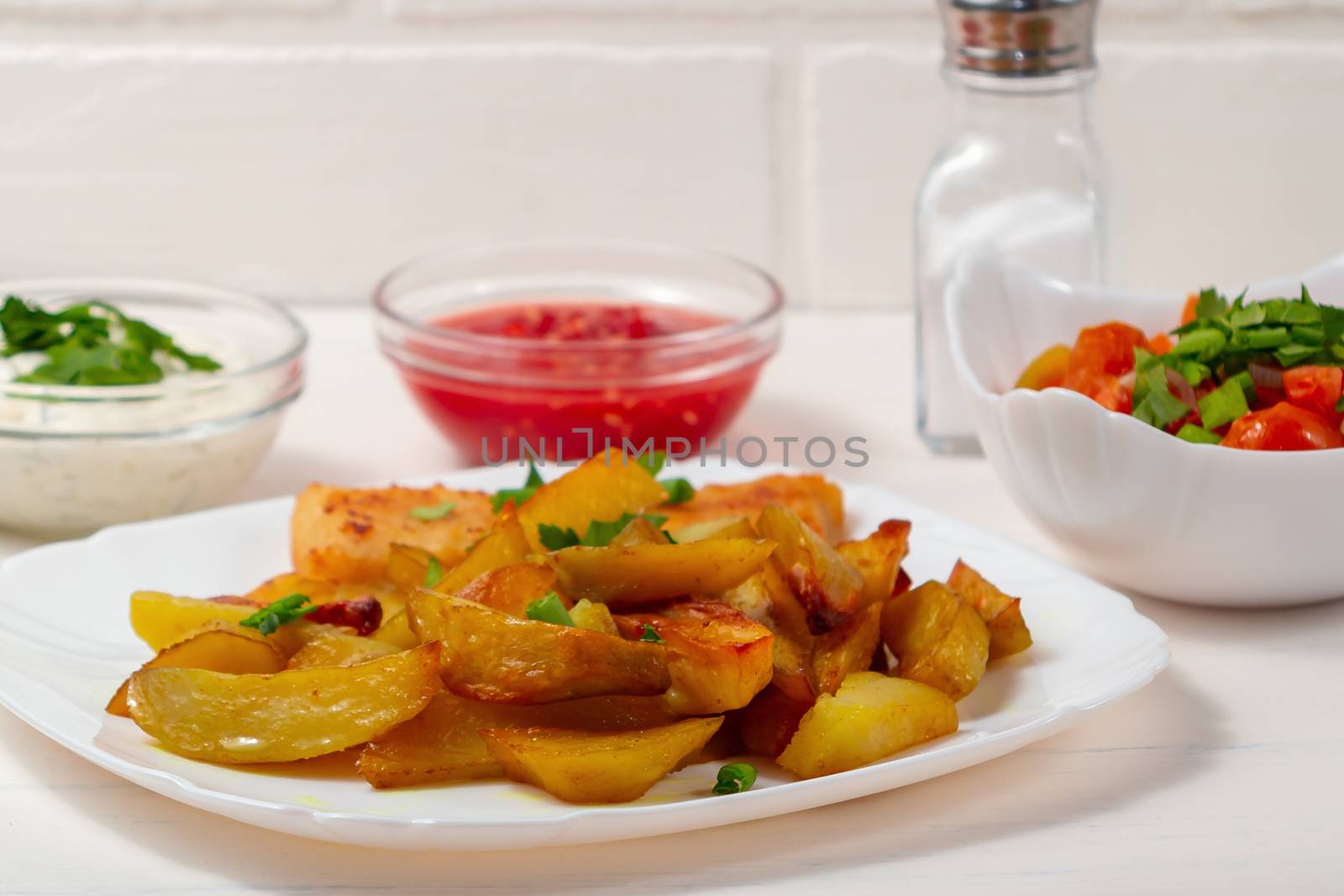 Fried fish and chips on a white plate on the kitchen table with tomato sauce, tartar sauce and pickled vegetables salad - photo, image by galsand