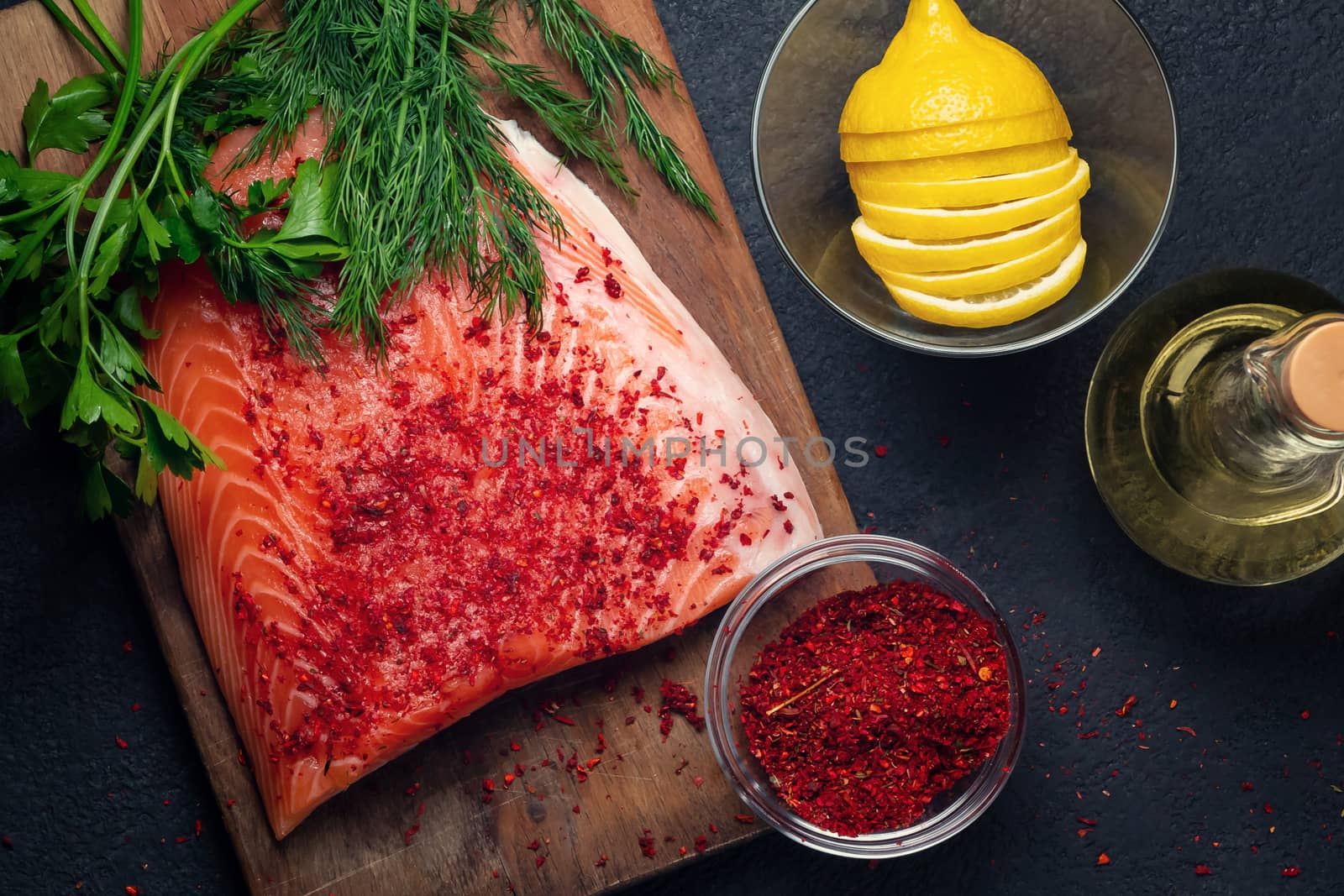 Piece of salmon fillet on a wooden cutting board with ingredients for its further preparation, top view - photo, image.