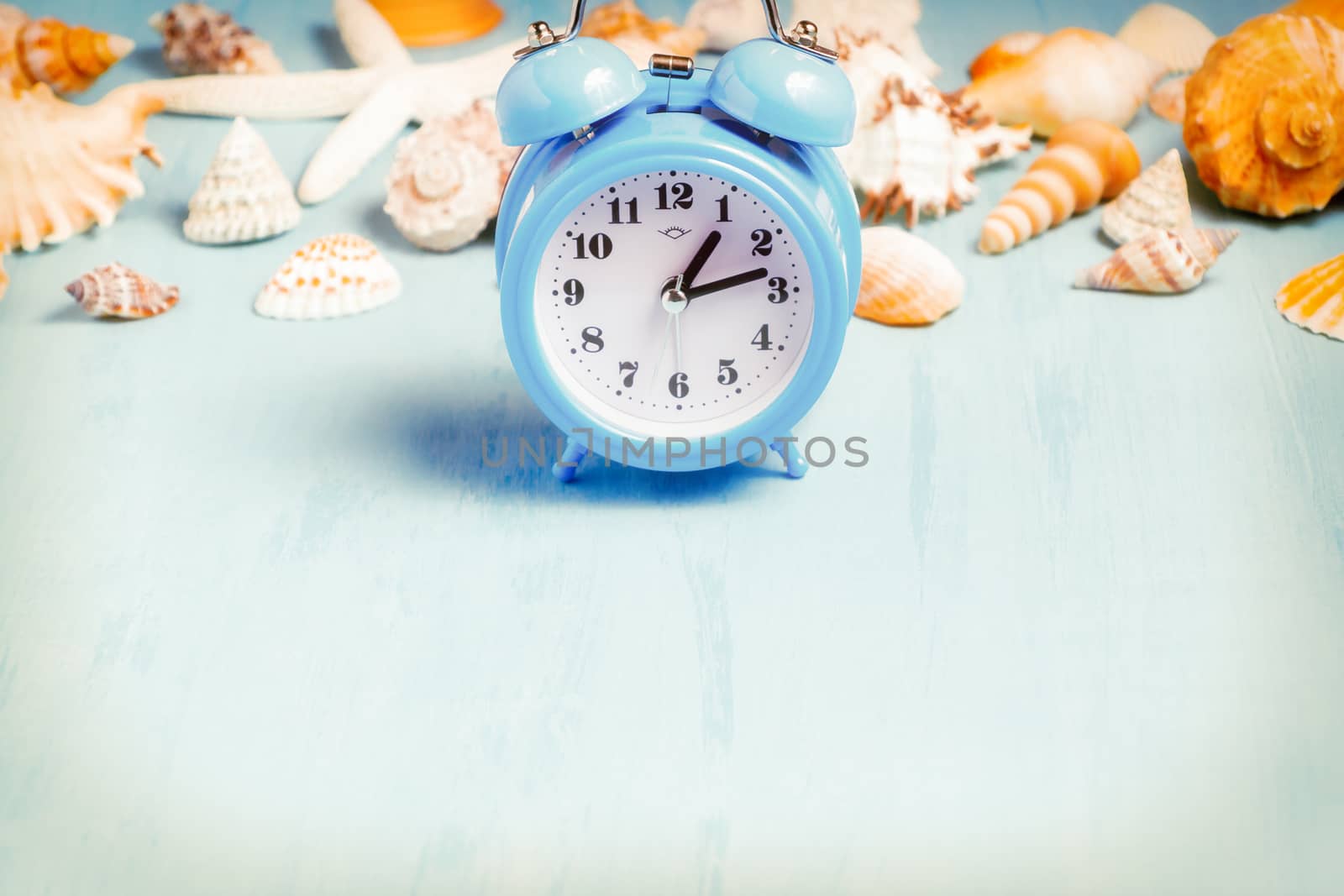 Blue sea background with alarm clocks and seashells, summer holiday and vacation time concept.