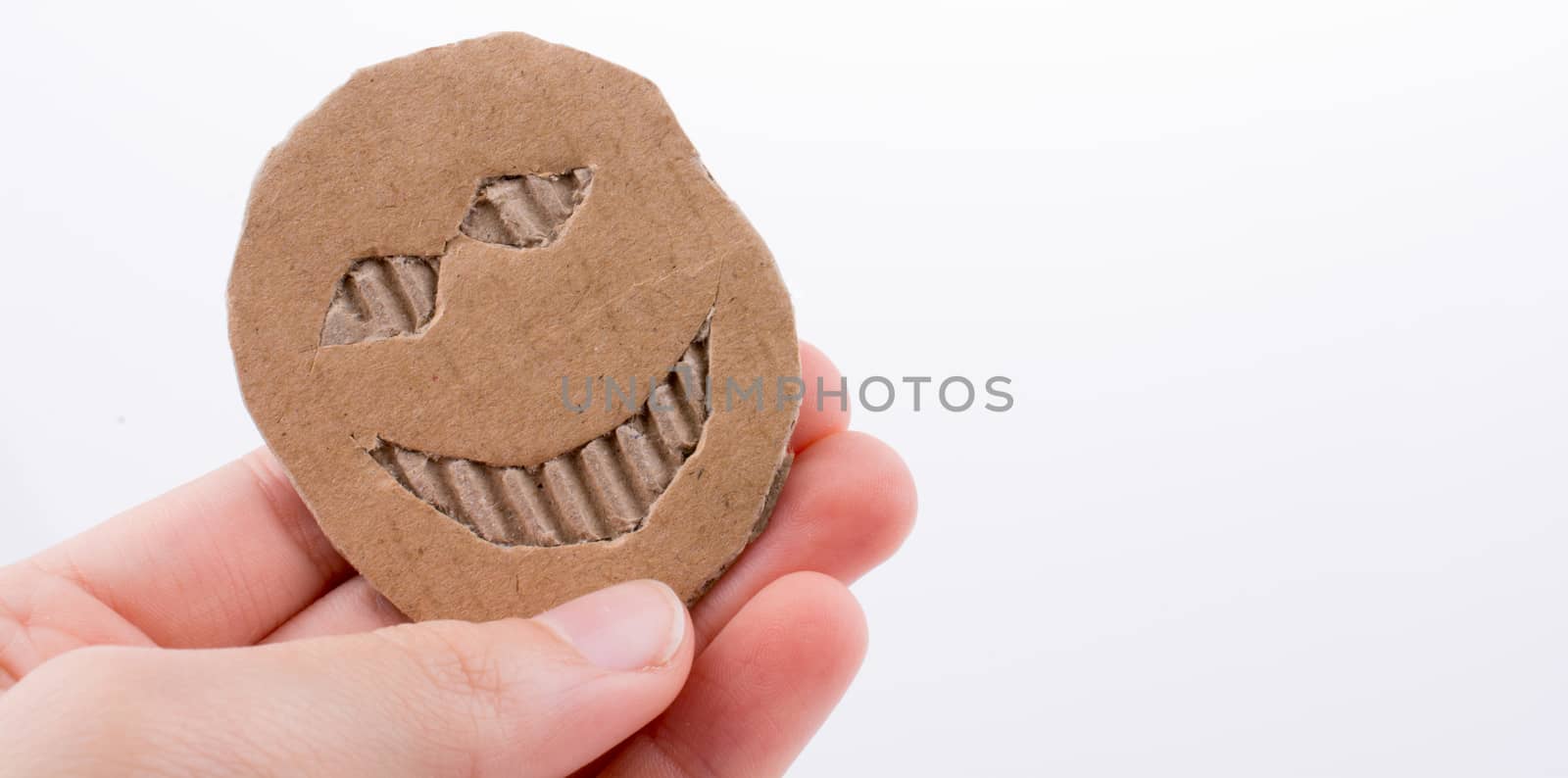 Hand holding a cardboard paper with smiley face by berkay