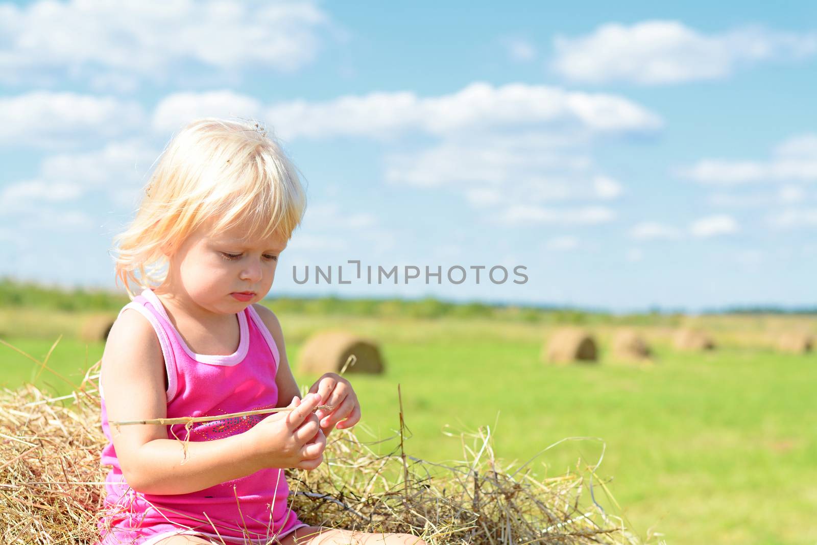 Rural Girl On The Straw After Harvest Field With Straw Bales