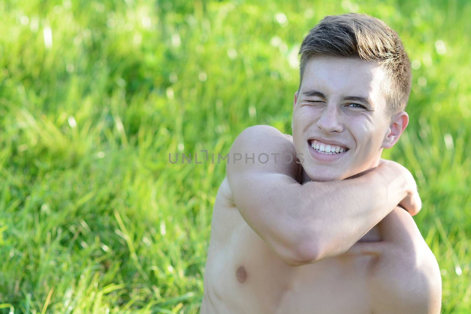 Good looking shirtless fit male model relaxing on the grass