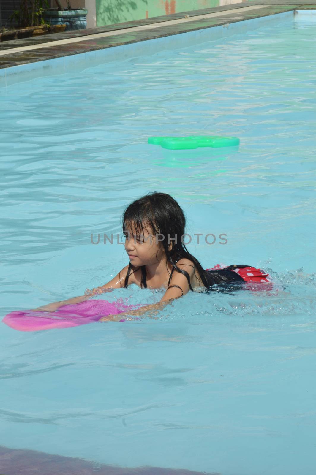 asian little girl playing in the pool by antonihalim