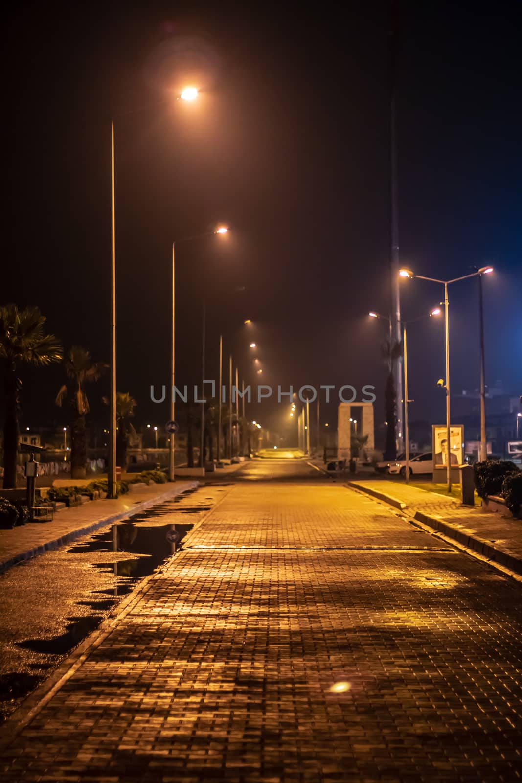 a good looking shoot from a coast road - wet stone road under city lights. photo has taken at izmir/turkey.