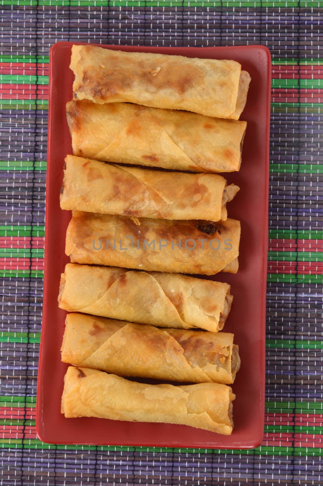 lumpia Semarang or Spring Rolls containing bamboo shoots and chicken on red plate at white background 