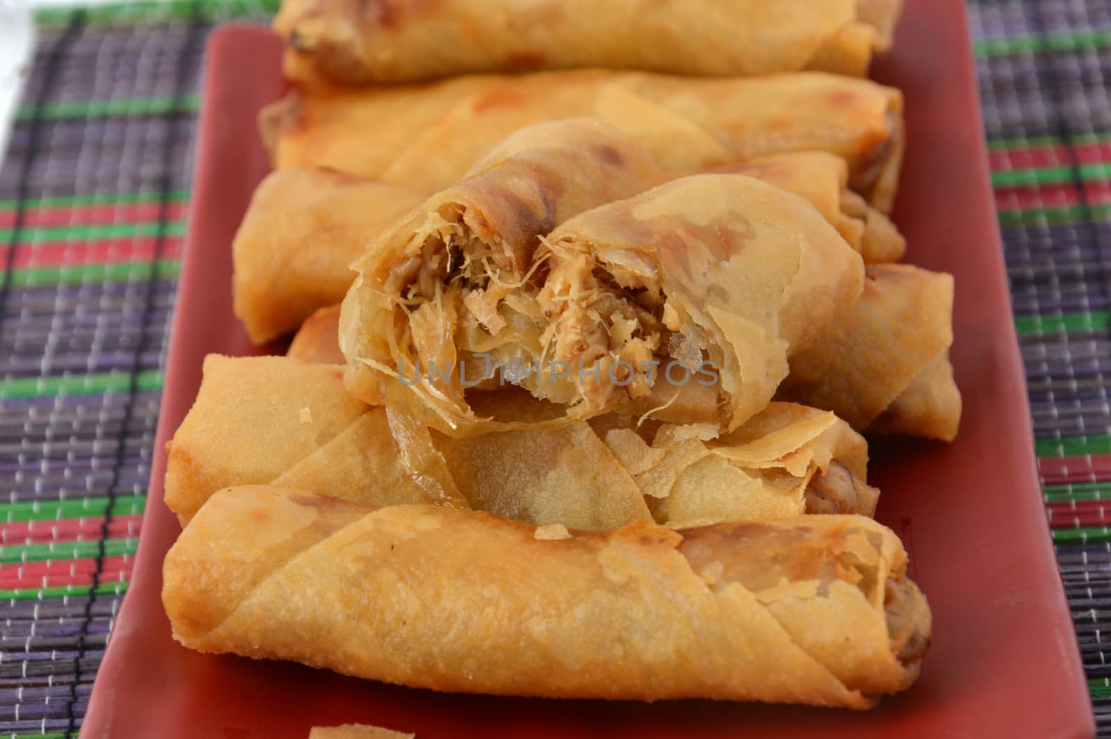 lumpia Semarang or Spring Rolls containing bamboo shoots and chicken on red plate at white background 