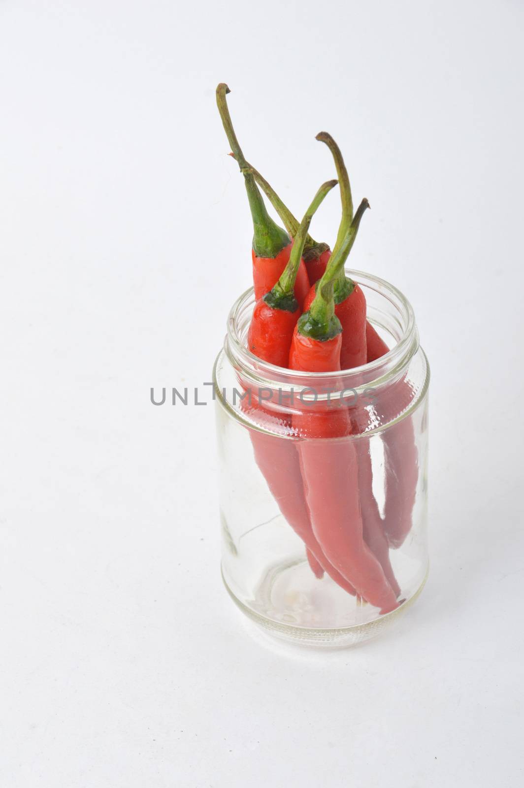 big chili red in a glass jar on white background