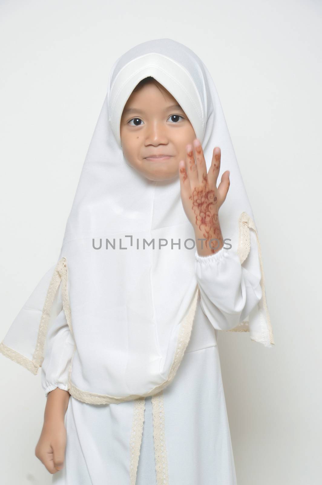 Moslem Asian little girl dressed with hijab in white with henna at her hand