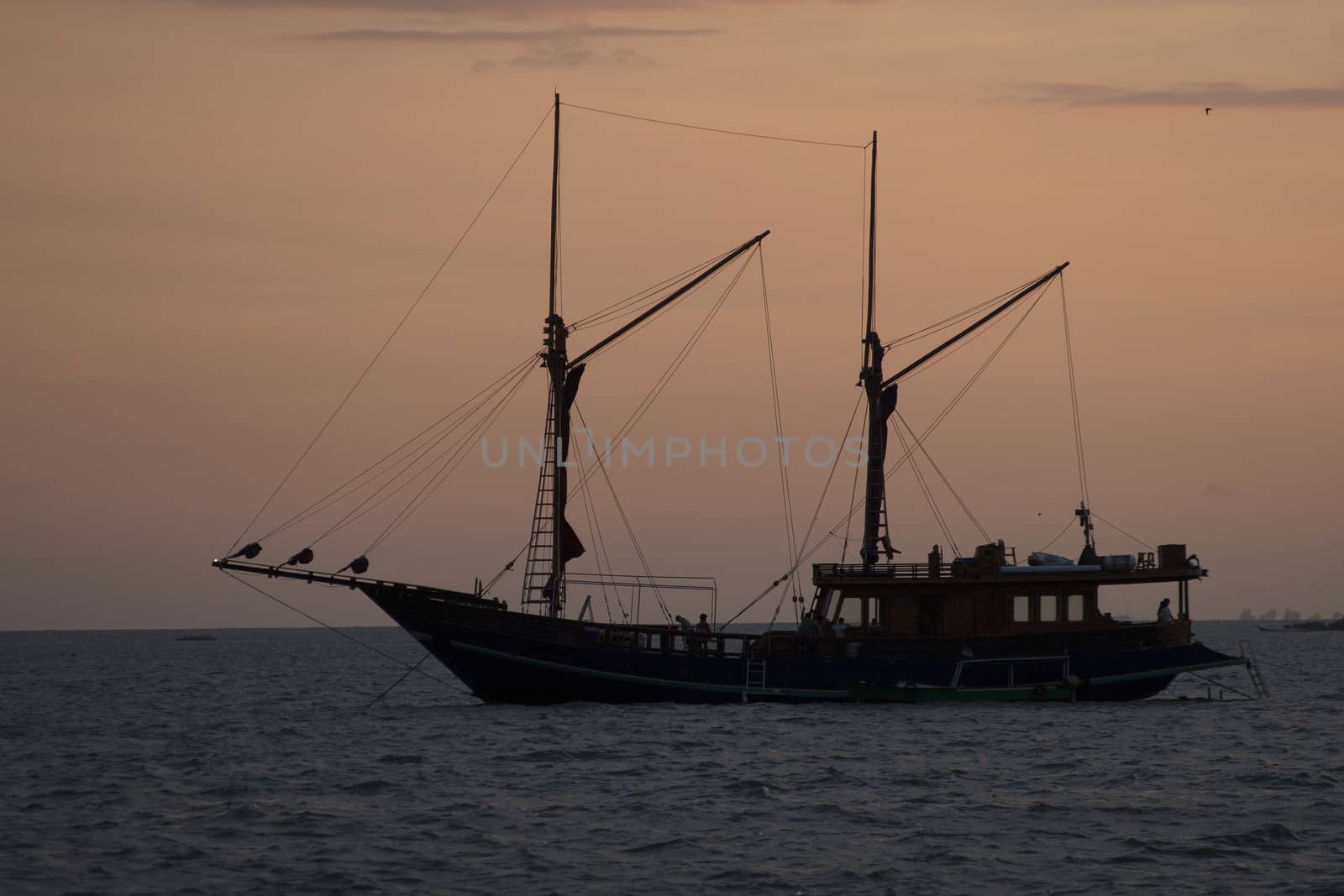 silhouette phinisi wooden ship at sunset, a traditional wooden boat from Sulawesi Indonesia