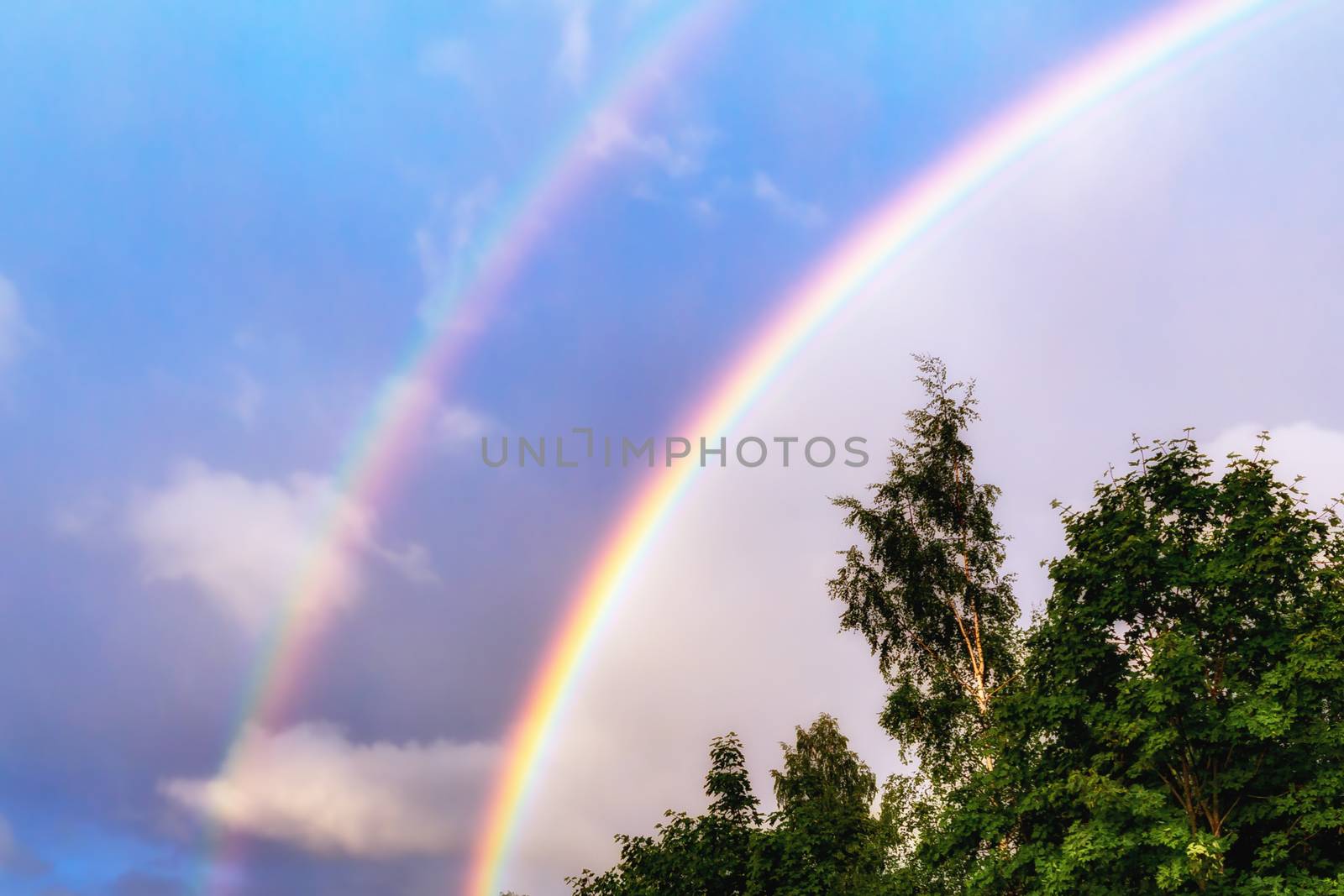 Rainbow after rain in a cloudy sky among dramatic clouds by galsand