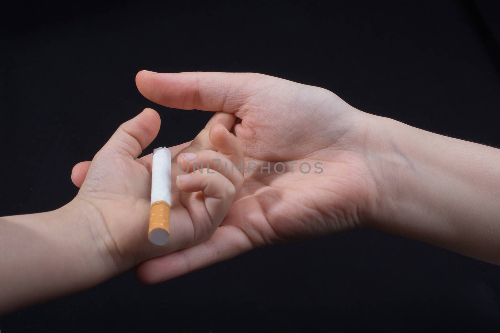 Hand is giving out cigarette on a black background