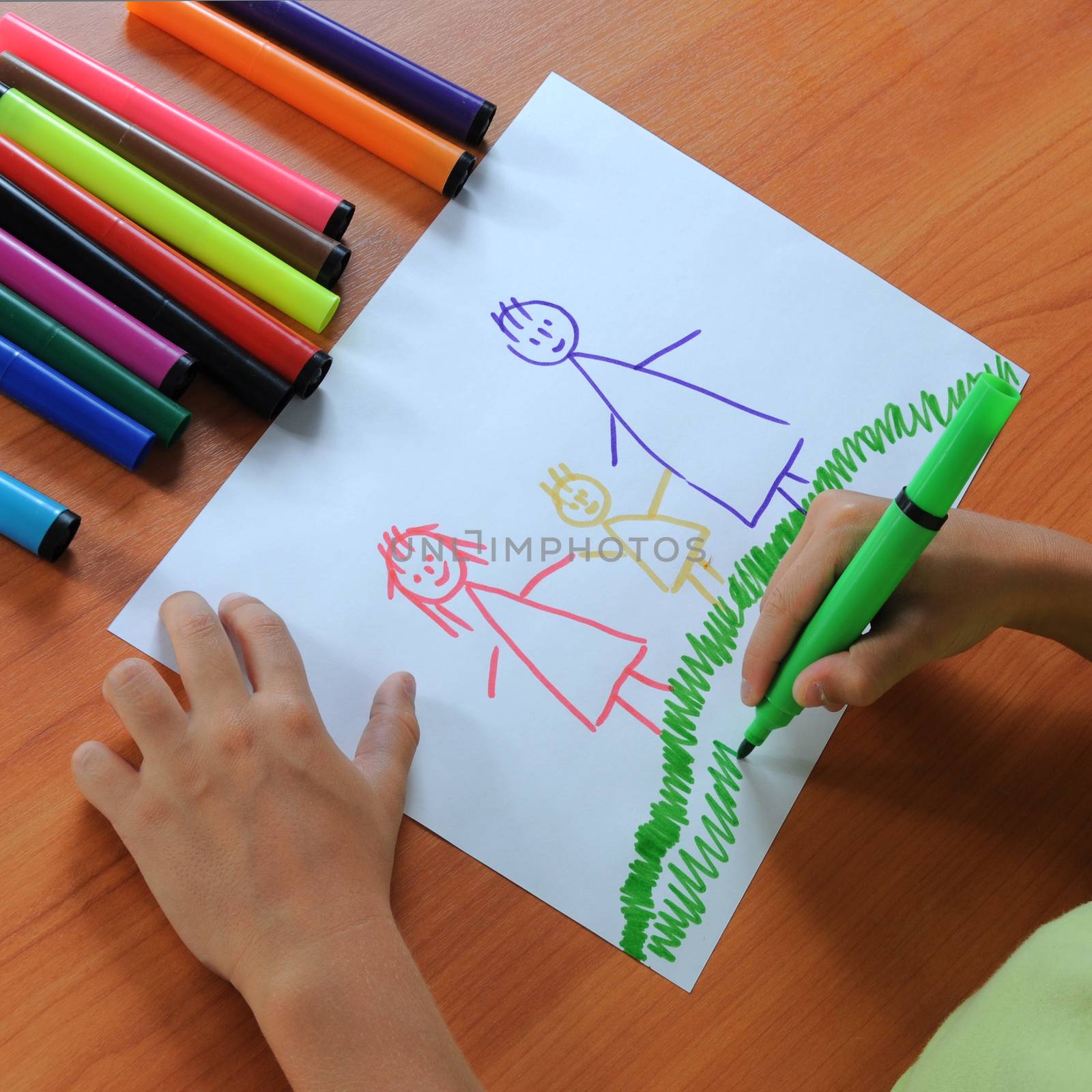 The child drawing a family on paper in colours