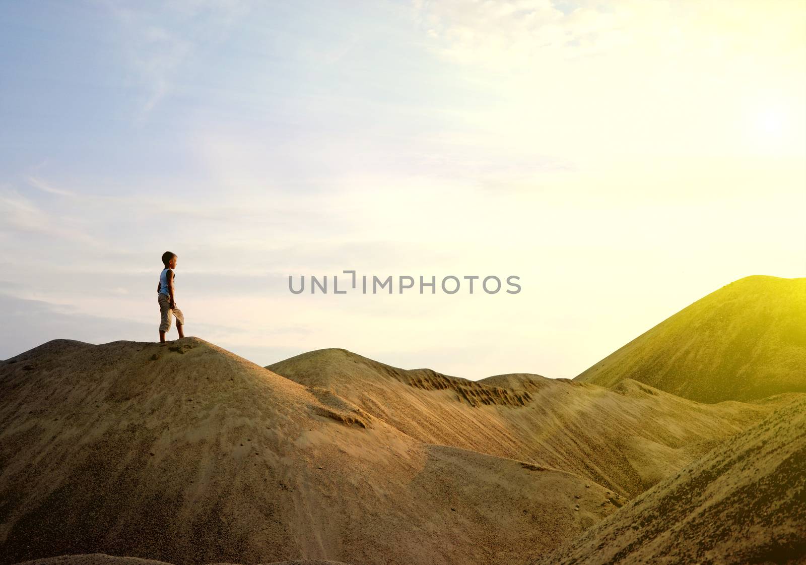 young man walking alone during sunrise on the mountain in a majestic summer sunse