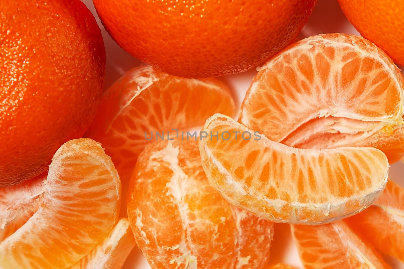 Several whole and peeled ripe tangerines on a white plate by galsand